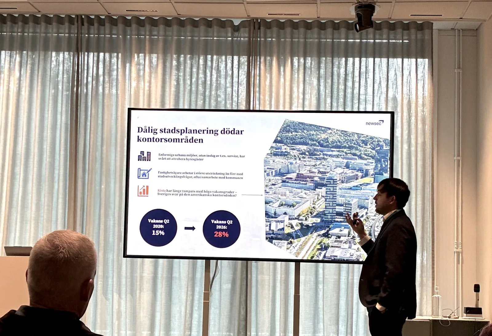 Adam Tyrcha talar framför en Newsec-bild om stadsplanering och kontorsområden.