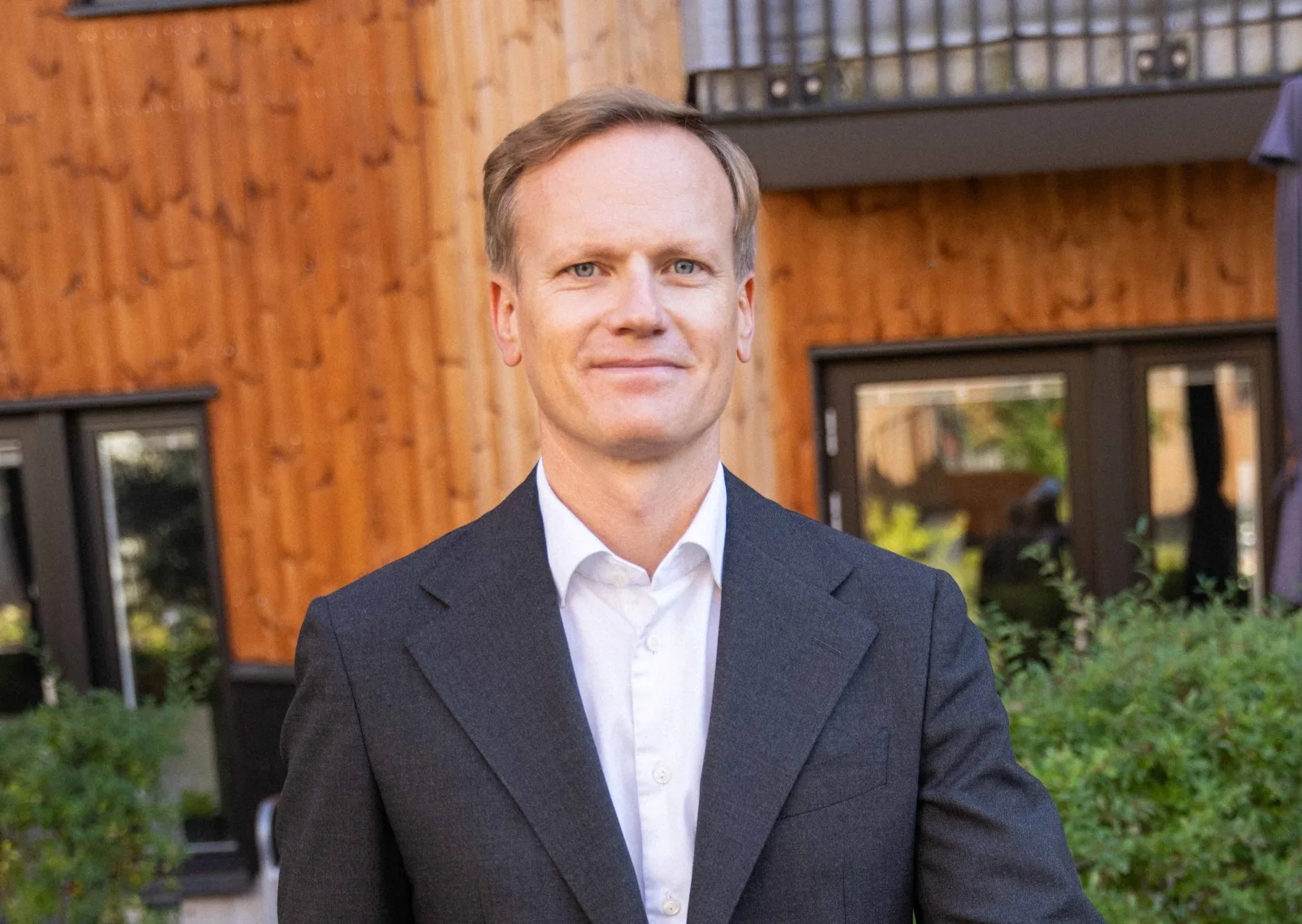 Erik Hävermark i kostym framför en trähusfasad.